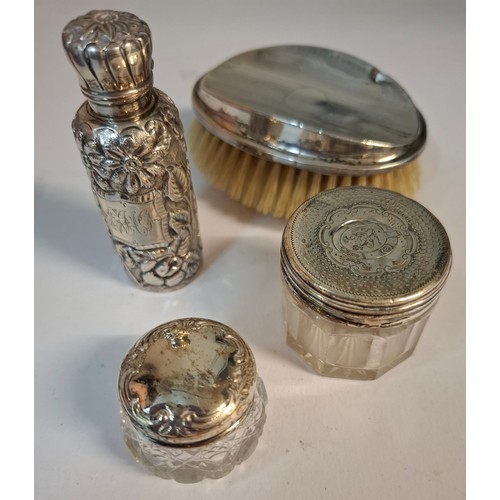 25 - Four silver dressing table items comprising 2 glass pots with silver lids, a circa 1900 silver embos... 