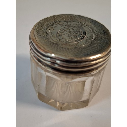 25 - Four silver dressing table items comprising 2 glass pots with silver lids, a circa 1900 silver embos... 
