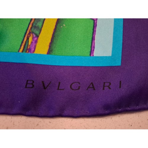 6 - Bulgari/Bvlgari- A silk scarf in tones of turquoise, purple, green and gold having the brand name in... 