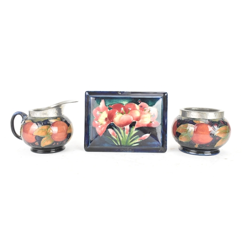 104 - A group of early/mid 20th century Moorcroft pottery to include a 'pomegranate' patter pewter mounted... 