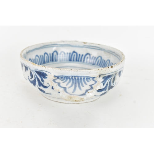 185 - An 18th century Delft faience porringer, painted in underglaze blue with flowering branches and foli... 