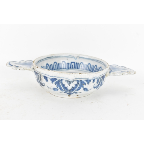 185 - An 18th century Delft faience porringer, painted in underglaze blue with flowering branches and foli... 