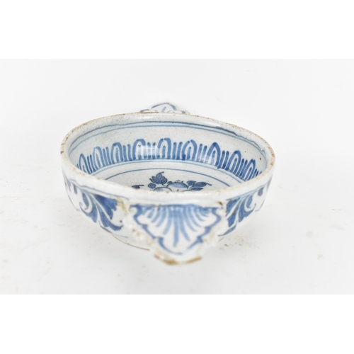 185 - An 18th century Delft faience porringer, painted in underglaze blue with flowering branches and foli... 