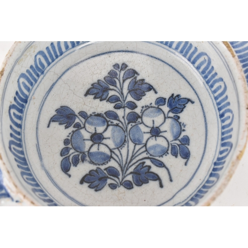 185 - An 18th century Delft faience porringer, painted in underglaze blue with flowering branches and foli... 