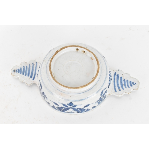 185 - An 18th century Delft faience porringer, painted in underglaze blue with flowering branches and foli... 