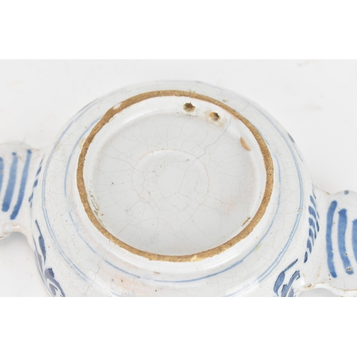 185 - An 18th century Delft faience porringer, painted in underglaze blue with flowering branches and foli... 