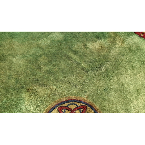 207 - An early 20th century hand-knotted Donegal carpet, the green field centred by a red and blue knotwor... 