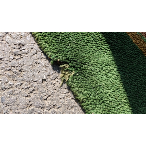 207 - An early 20th century hand-knotted Donegal carpet, the green field centred by a red and blue knotwor... 