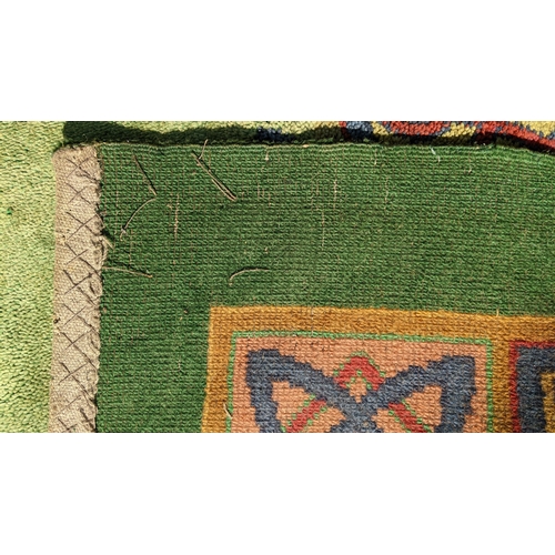 207 - An early 20th century hand-knotted Donegal carpet, the green field centred by a red and blue knotwor... 