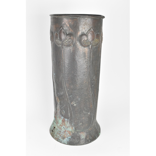 72 - An Arts & Crafts copper stick stand, having six tulip headed flowers rising on long stalks against a... 