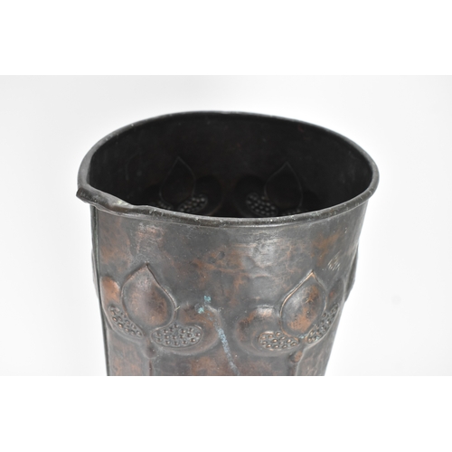 72 - An Arts & Crafts copper stick stand, having six tulip headed flowers rising on long stalks against a... 