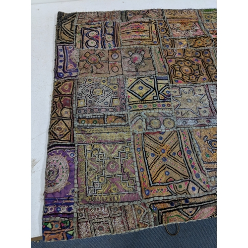 54 - An oriental style wall hanging with a variety of abstract patterns on a hanging pole 148 cm H x 72 c... 