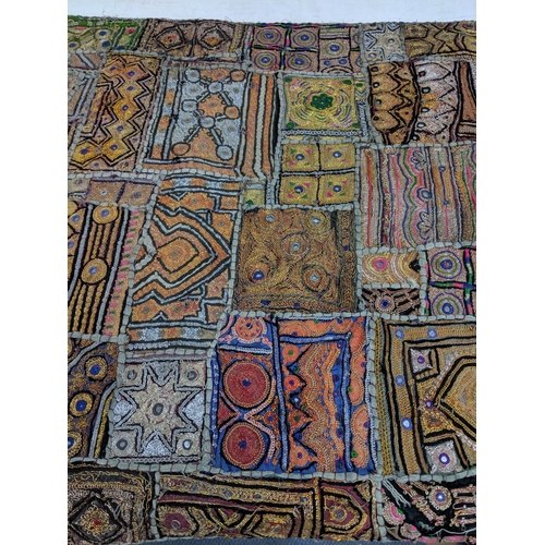 54 - An oriental style wall hanging with a variety of abstract patterns on a hanging pole 148 cm H x 72 c... 