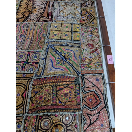 54 - An oriental style wall hanging with a variety of abstract patterns on a hanging pole 148 cm H x 72 c... 