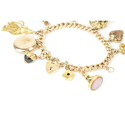 17 - A 9ct gold curb link bracelet,  fitted with a heart shaped catch and locket, a tassel, fob seals and... 