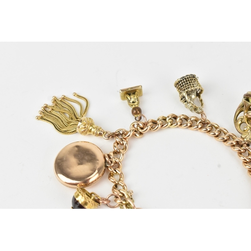 17 - A 9ct gold curb link bracelet,  fitted with a heart shaped catch and locket, a tassel, fob seals and... 