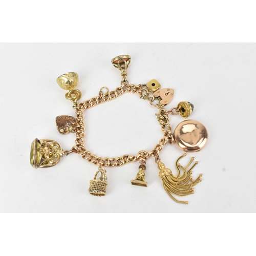 17 - A 9ct gold curb link bracelet,  fitted with a heart shaped catch and locket, a tassel, fob seals and... 