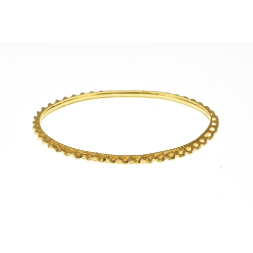 18 - A yellow gold textured bangle, with faceted barley twist detail and milled edge decoration, unmarked... 