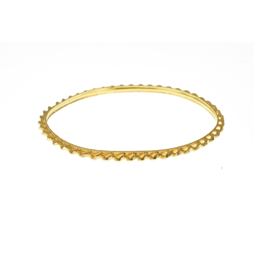 18 - A yellow gold textured bangle, with faceted barley twist detail and milled edge decoration, unmarked... 