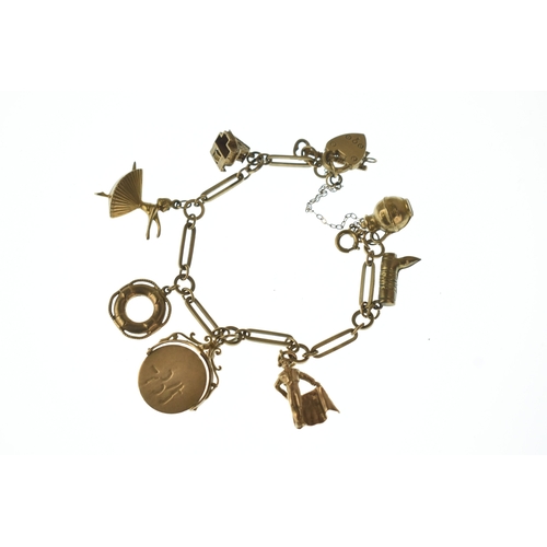 22 - A 9ct gold charm bracelet,  fitted with an assortment of charms including a key, boot, ballet dancer... 