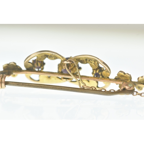 26 - An Edwardian seed pearl and amethyst 9ct gold bar brooch, the scrolling openwork panel set with thre... 