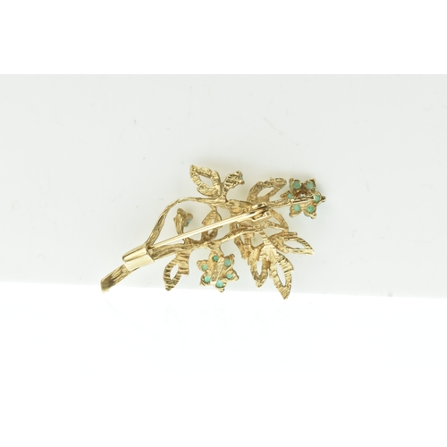 43 - An emerald and diamond 9ct gold brooch, modelled as a foliate spray with textured leaves and floral ... 
