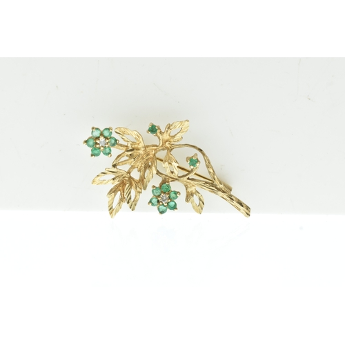 43 - An emerald and diamond 9ct gold brooch, modelled as a foliate spray with textured leaves and floral ... 