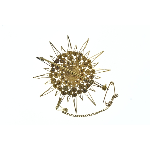 44 - A yellow gold starburst brooch, of multi-rayed design with applied concentric circular motifs and fi... 