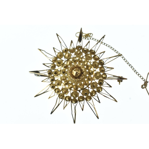 44 - A yellow gold starburst brooch, of multi-rayed design with applied concentric circular motifs and fi... 