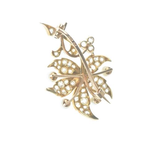 46 - A diamond and pearl 14ct gold floral brooch designed as a scrolling foliate spray set throughout wit... 