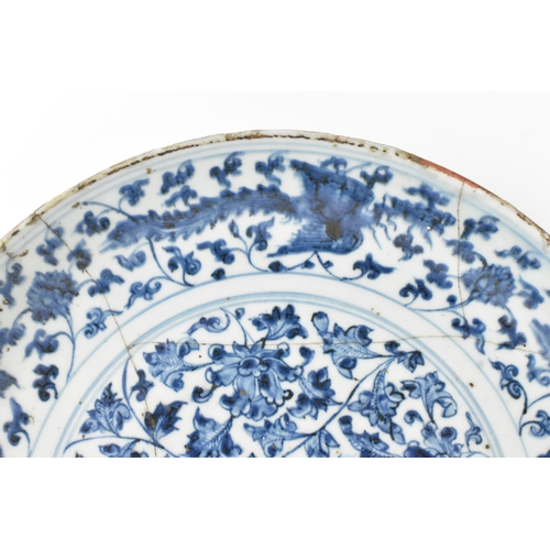 22 - A Chinese Ming dynasty blue and white charger, painted with a phoenix amidst scrolling peony and bir... 