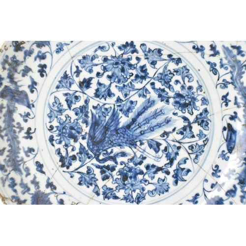 22 - A Chinese Ming dynasty blue and white charger, painted with a phoenix amidst scrolling peony and bir... 