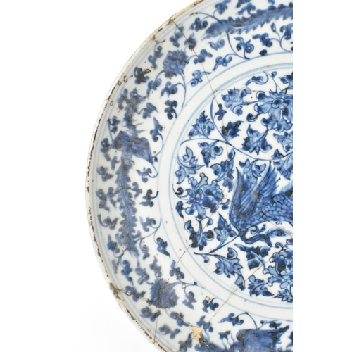22 - A Chinese Ming dynasty blue and white charger, painted with a phoenix amidst scrolling peony and bir... 