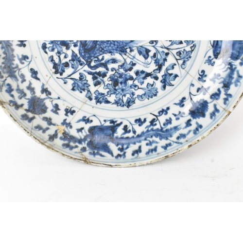 22 - A Chinese Ming dynasty blue and white charger, painted with a phoenix amidst scrolling peony and bir... 