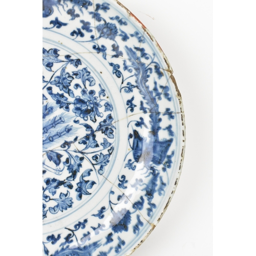 22 - A Chinese Ming dynasty blue and white charger, painted with a phoenix amidst scrolling peony and bir... 