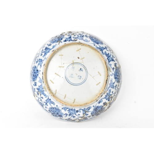 22 - A Chinese Ming dynasty blue and white charger, painted with a phoenix amidst scrolling peony and bir... 