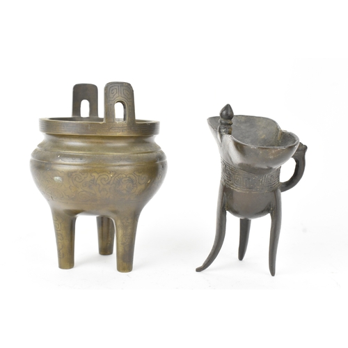 29 - A pair of Chinese bronze tripod vessels, comprising a ding with engraved decoration and an apocrypha... 