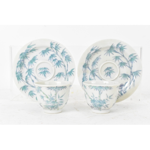45A - A pair of Chinese famille-verte porcelain cups and saucers, each cup of flared form, decorated with ... 