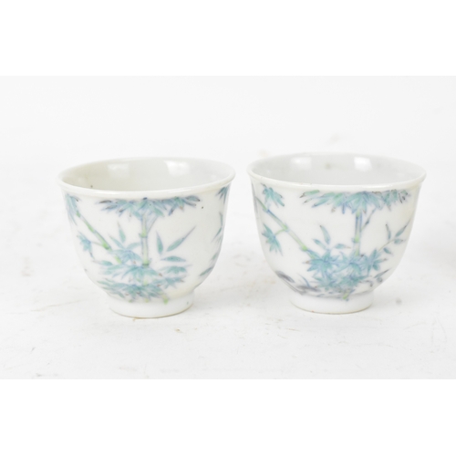45A - A pair of Chinese famille-verte porcelain cups and saucers, each cup of flared form, decorated with ... 