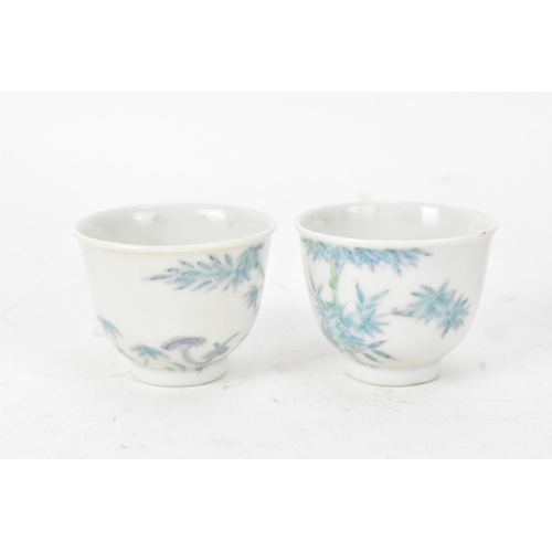 45A - A pair of Chinese famille-verte porcelain cups and saucers, each cup of flared form, decorated with ... 