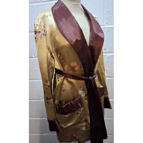 41 - A 1940's Japanese gold coloured satin smoking jacket having machine embroidered images of floral spr... 