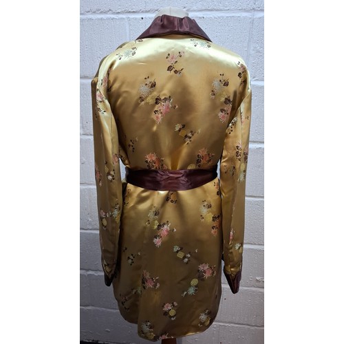 41 - A 1940's Japanese gold coloured satin smoking jacket having machine embroidered images of floral spr... 