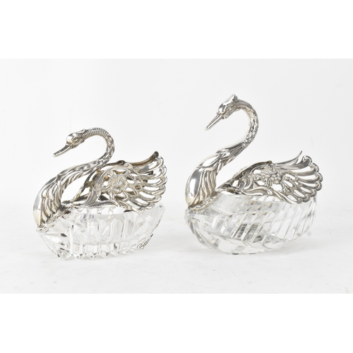 A pair of Elizabeth II silver-mounted cut glass swan salts, makers marks for E Ltd, both with London import marks, one hallmarked 1965 and the other 1973. Each formed as a swan with pierced and cast silver wings and neck, the bodies of cut glass,  the taller example 12.5cm high, the smaller 10cm high 
If there is no condition report shown, please request