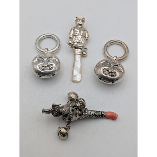 113 - A group of baby rattles to include a silver mother of pearl example, fashioned as a cat, a coral and... 