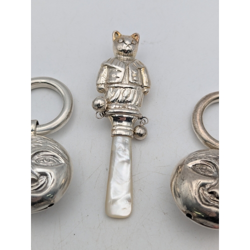 113 - A group of baby rattles to include a silver mother of pearl example, fashioned as a cat, a coral and... 