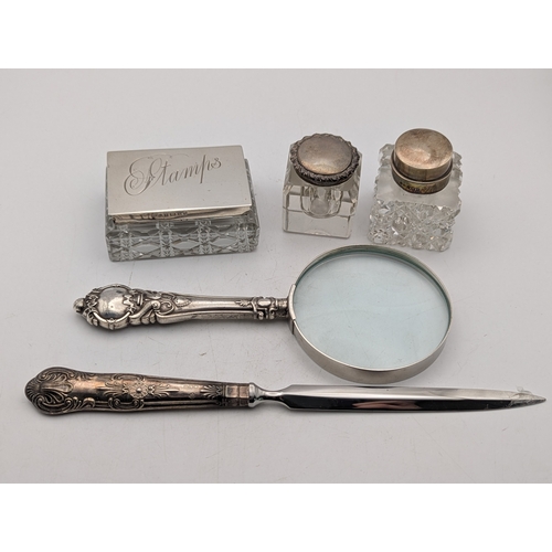 114 - A group of silver topped and silver handled desk top items to include a stamp pot, two ink pots, a l... 