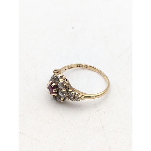 75 - A ruby and diamond 14ct yellow gold cluster ring, set with a central claw set ruby surrounded by dia... 