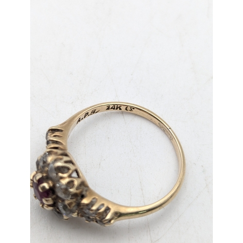 75 - A ruby and diamond 14ct yellow gold cluster ring, set with a central claw set ruby surrounded by dia... 
