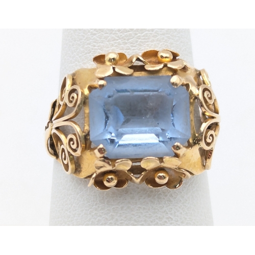 78 - An aquamarine and 18ct yellow gold ring having a floral pierced design and scroll pierced shoulders ... 