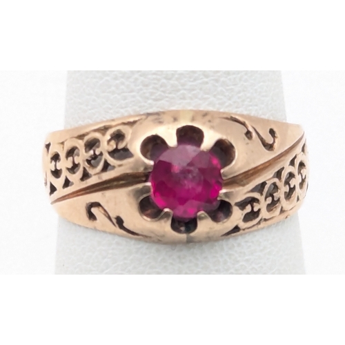80 - A ruby and rose gold ring tested as 9ct having pierced design to the shoulders on a tapering shank s... 